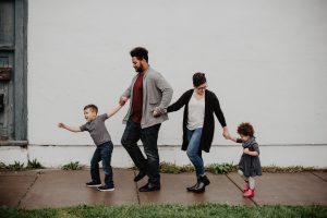 Two parents with two young children walking down the street in the rain